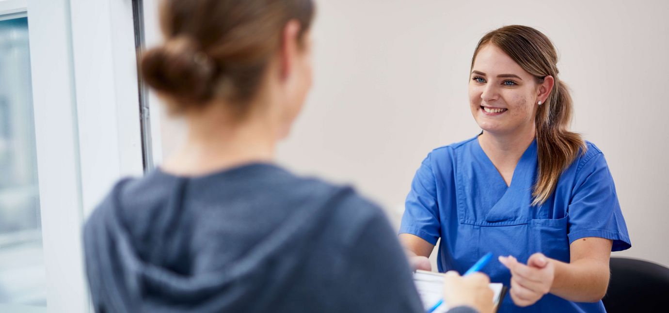 Medinische Fachangestelle spricht mit Patientin