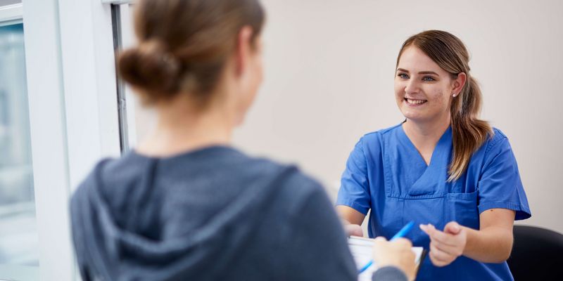 Medinische Fachangestelle spricht mit Patientin